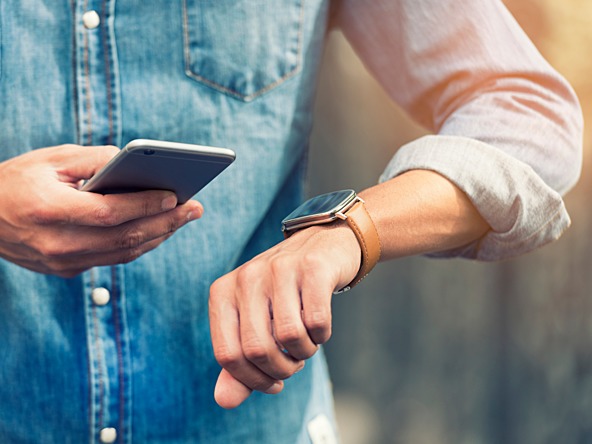 Man looking at phone while checking watch